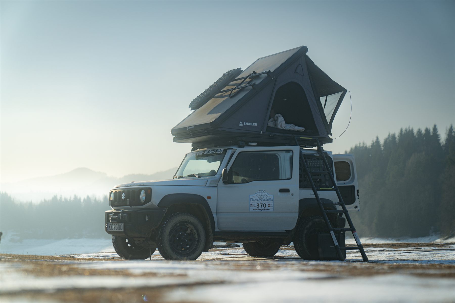 Roof tent open on a car parked in snow, elevated above the cold ground