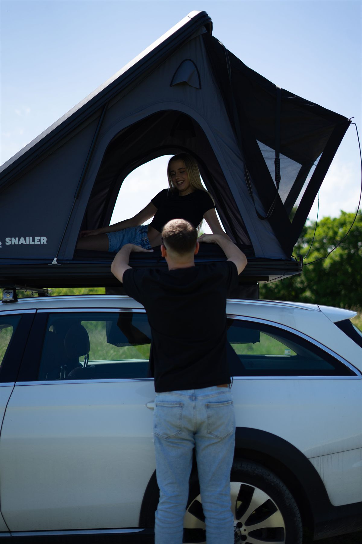 Man opening a large Snailer roof tent on a car roof